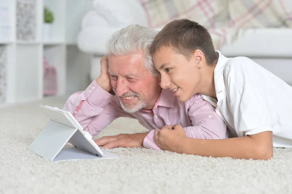 Dziadek Wnukiem Pomocą Tabletu Leżąc Podłodze Domu — Zdjęcie stockowe