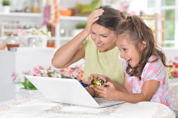 可爱的小女孩的肖像与年轻的母亲玩电脑游戏与笔记本电脑在家里 — 图库照片