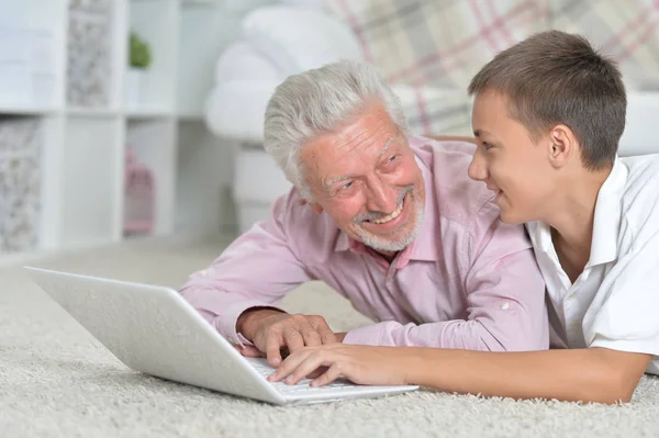 Abuelo Con Nieto Usando Ordenador Portátil Mientras Está Acostado Suelo —  Fotos de Stock