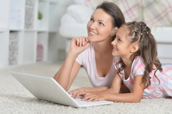 幸せな母と娘一緒に家の床に横たわっている間ノート パソコンを使用して — ストック写真