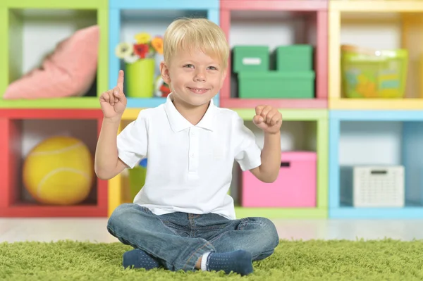 金发小男孩的肖像坐在绿色的地毯上 用手指 — 图库照片