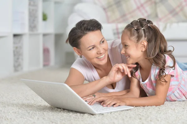 幸せな母と娘一緒に家の床に横たわっている間ノート パソコンを使用して — ストック写真
