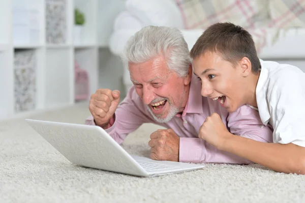 Avô Com Neto Usando Laptop Enquanto Deitado Chão Casa — Fotografia de Stock