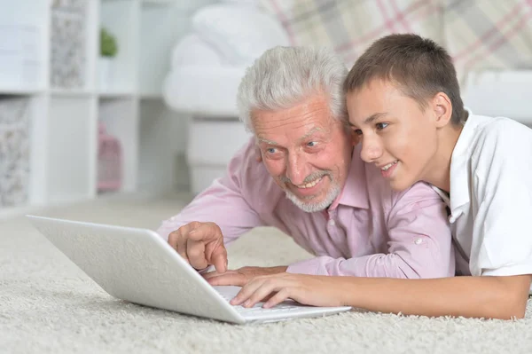 Abuelo Con Nieto Usando Ordenador Portátil Mientras Está Acostado Suelo —  Fotos de Stock