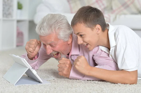 Avô Com Neto Usando Tablet Enquanto Deitado Chão Casa — Fotografia de Stock