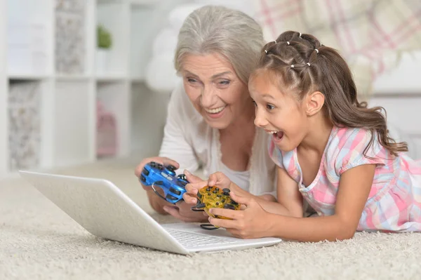 可爱的小女孩与她的祖母玩电脑游戏与笔记本电脑 — 图库照片
