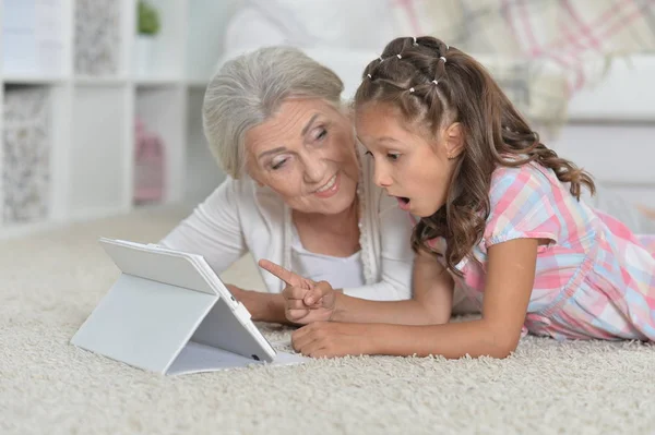 Dziewczyna z babcia za pomocą tabletu — Zdjęcie stockowe