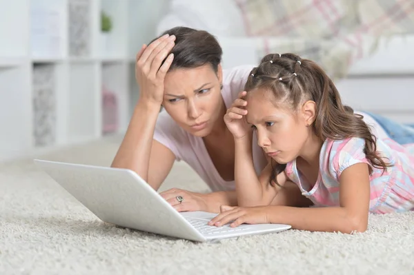 在家里躺在地板上时 母亲和女儿一起使用笔记本电脑 — 图库照片