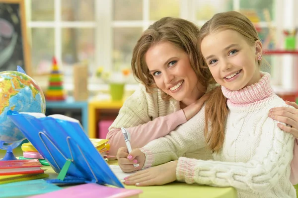 可爱的女孩与她的母亲一起做家庭作业 — 图库照片