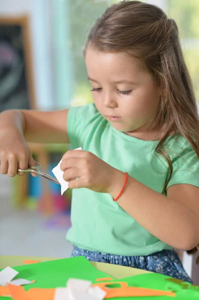 Llittle girl is cutting color paper — Stock Photo, Image