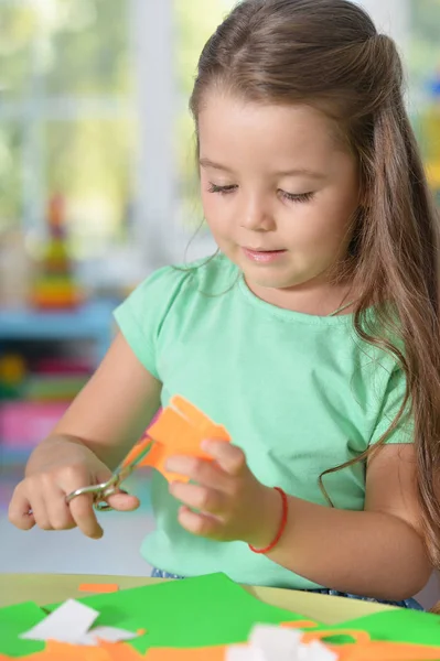 Llittle girl is cutting color paper — Stock Photo, Image