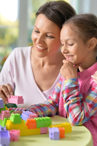 小さな女の子と彼女の母親は カラフルなプラスチック製のブロックで遊んで — ストック写真