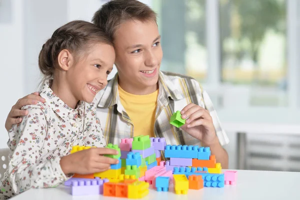 兄と妹は一緒にカラフルなプラスチックブロックで遊んで — ストック写真