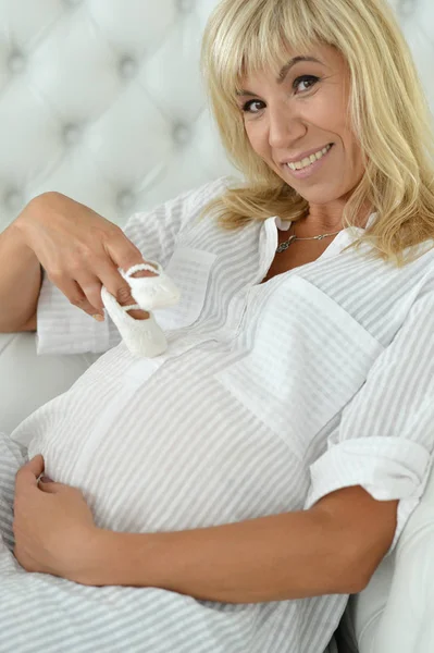 Mooie Zwangere Vrouw Poseren Met Babyslofjes Thuis — Stockfoto