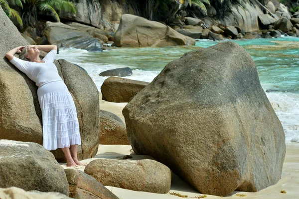 成熟的女人站在沙滩与岩石的肖像 — 图库照片