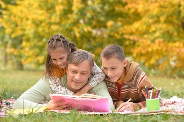 Kitap ile parkta oturan aile — Stok fotoğraf