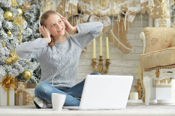 Noel Ağacı Yanında Otururken Dizüstü Kullanarak Kulaklık Ile Genç Kız — Stok fotoğraf
