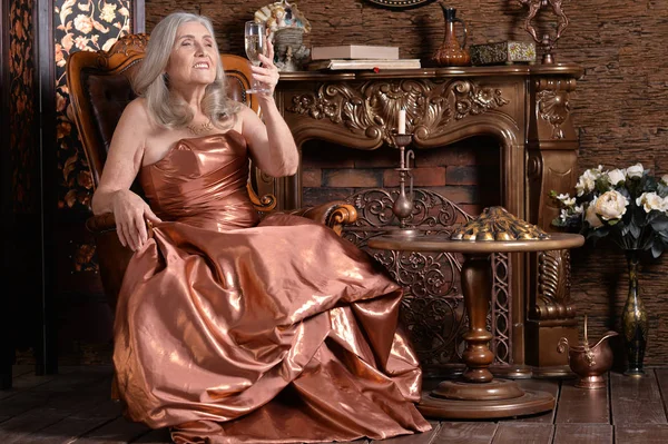 美丽的高级妇女在金色礼服与香槟 — 图库照片