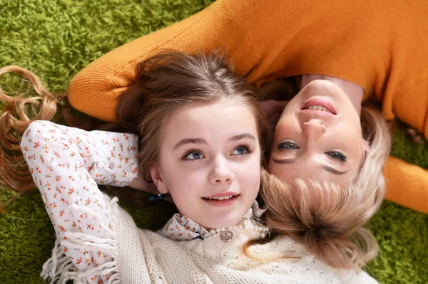 幸福的母亲与女儿躺在绿色的地毯在家里 — 图库照片