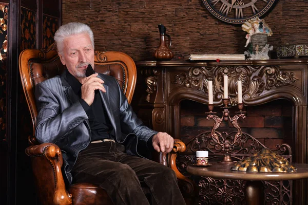 Zamyšleně Starší Muž Který Držel Smartphone Zatímco Sedí Křesle Vintage — Stock fotografie