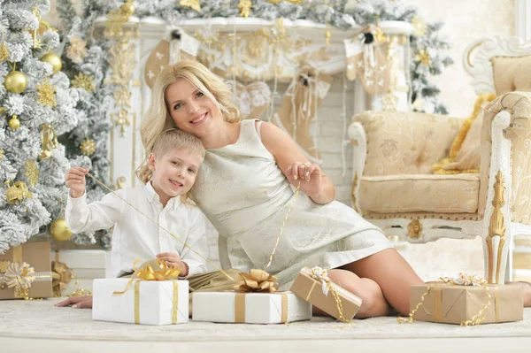 与儿子摆在房间装饰的圣诞节美丽的年轻妇女的肖像 — 图库照片