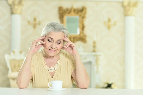 テーブルに白いカップと座って美しい年配の女性の肖像画 — ストック写真