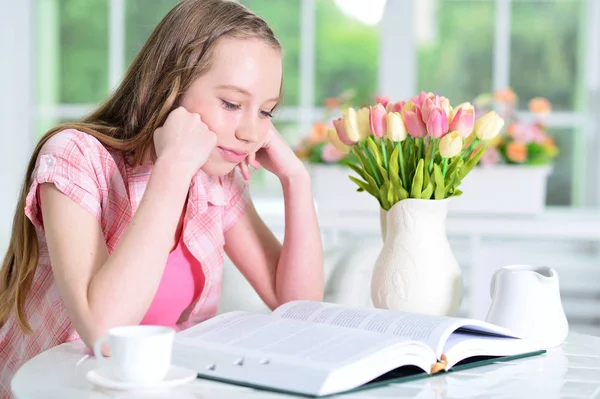 Χαριτωμένο Μαθήτρια Κάθεται Στο Τραπέζι Και Διάβασμα Στο Σπίτι — Φωτογραφία Αρχείου