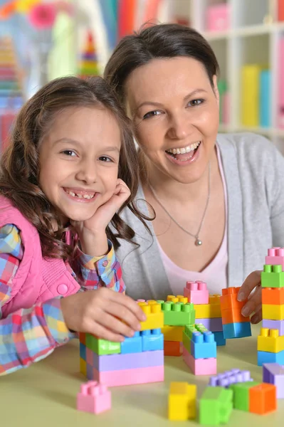 小さな女の子と彼女の母親は カラフルなプラスチック製のブロックで遊んで — ストック写真