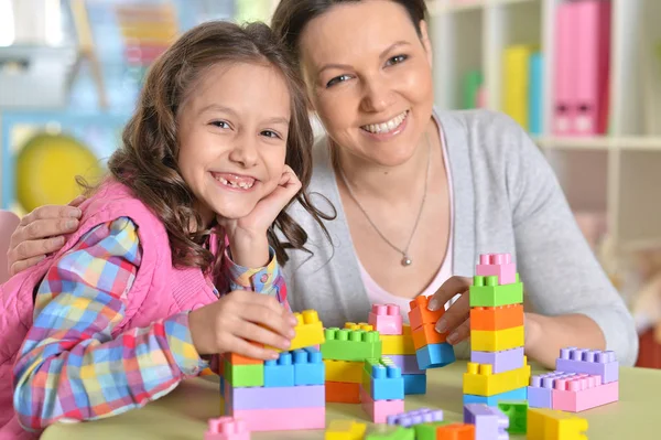 小さな女の子と彼女の母親は カラフルなプラスチック製のブロックで遊んで — ストック写真