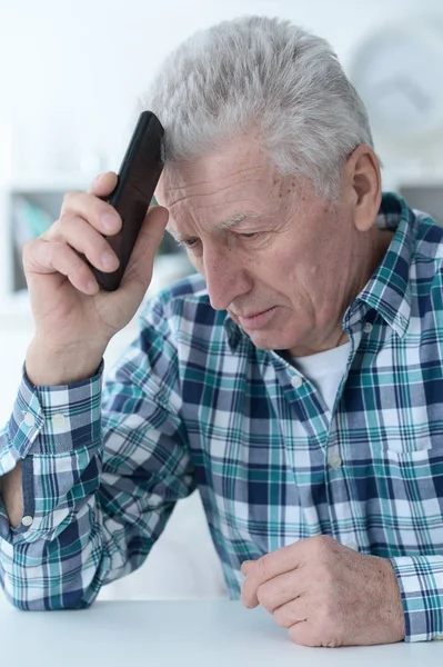 Homem idoso com telefone em casa — Fotografia de Stock