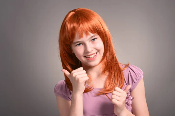 親指でスタジオでポーズをとって赤い髪のかわいい少女の肖像画 — ストック写真