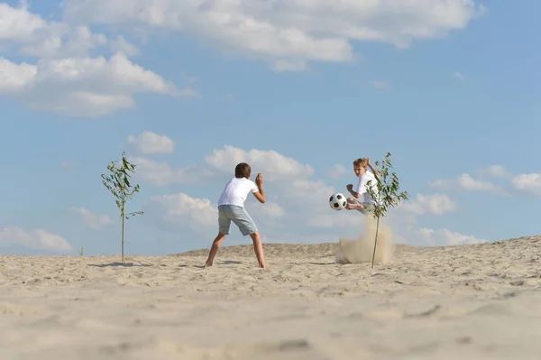 夏の日にビーチでサッカーをしている二人の兄弟 — ストック写真