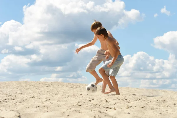 夏の日にビーチでサッカーをしている二人の兄弟 — ストック写真