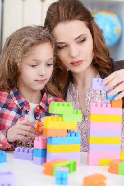 かわいい女の子と彼女の母親が彼女の部屋でカラフルなプラスチック製のブロックを一緒に遊んで — ストック写真