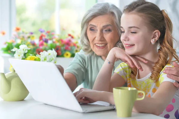 Flicka med mormor använder laptop — Stockfoto