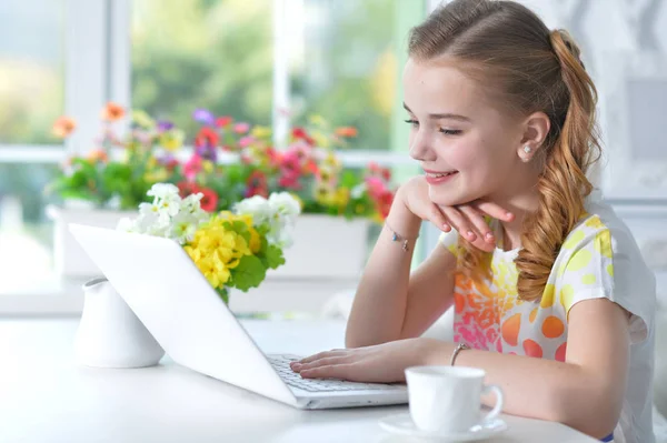 Ragazza seduta a tavola con computer portatile — Foto Stock