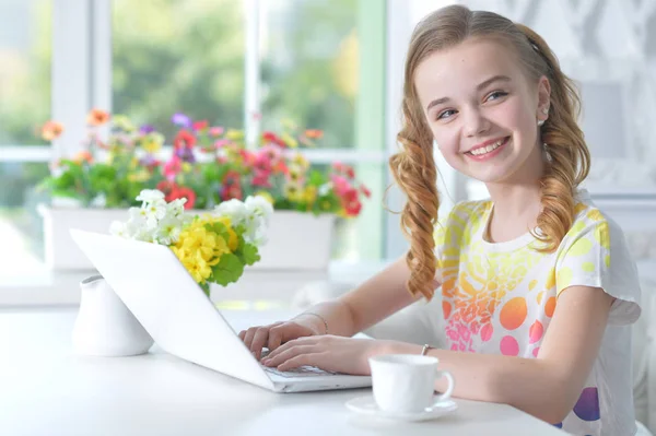 Meisje zit aan tafel met laptop — Stockfoto