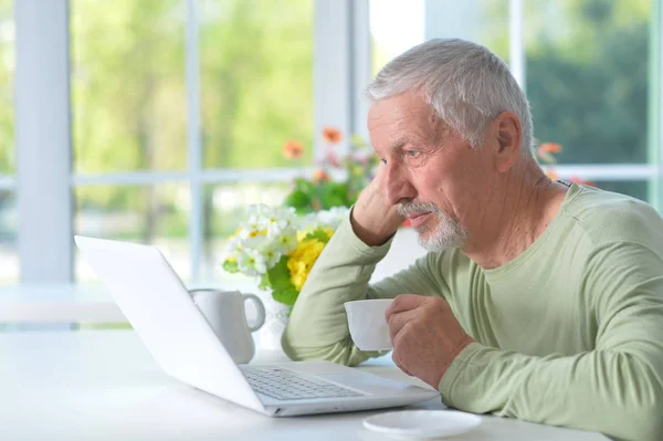 Starszy Człowiek Korzysta Laptopa Podczas Picia Herbaty Domu — Zdjęcie stockowe