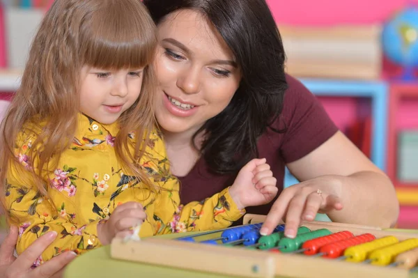 Mother teaching daughter to use abacus
