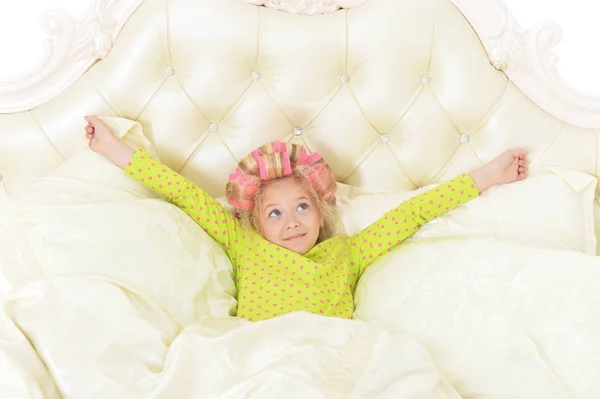 自宅のベッド上で楽しんでピンクのカーラーで素敵な女の子 — ストック写真