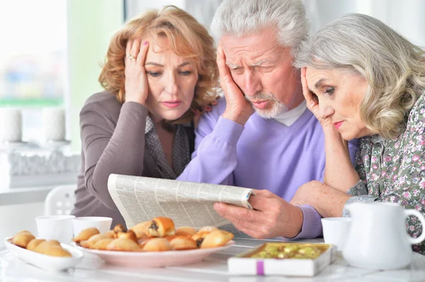 Sad Senior People Reading Newspaper While Drinking Tea Cookies Kitchen — Stock Photo, Image