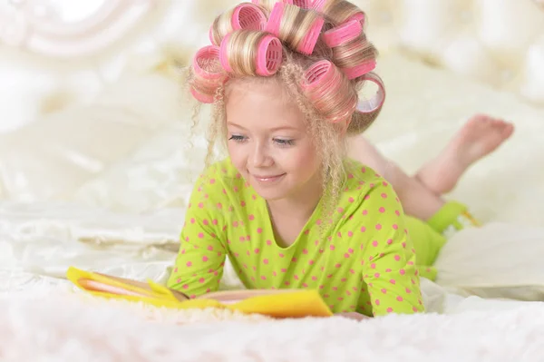 Preciosa Niña Con Rizadores Rosados Leyendo Cama Casa —  Fotos de Stock