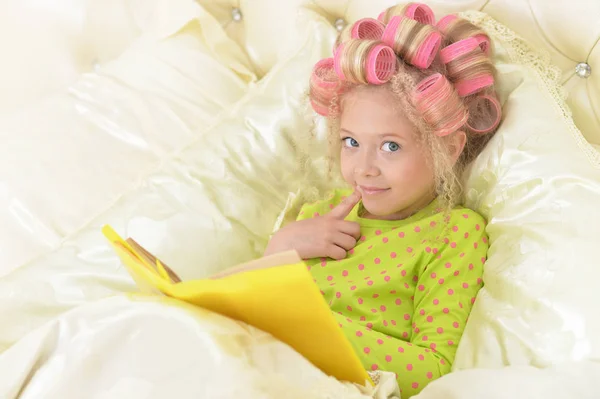 Preciosa Niña Con Rizadores Rosados Leyendo Cama Casa —  Fotos de Stock