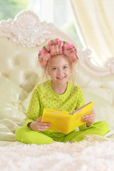 Милая Маленькая Девочка Розовыми Бигудями Читает Постели Дома — стоковое фото