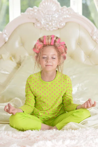 Schöne Kleine Mädchen Mit Rosa Lockenwickler Meditieren Auf Dem Bett — Stockfoto