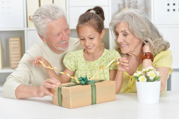 Grandparents and granddaughter with big gift box