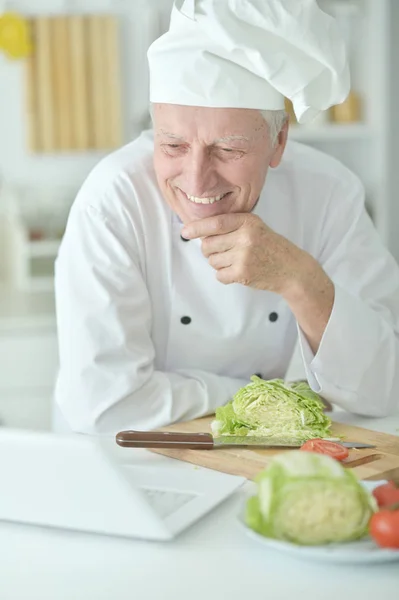 Äldre Manlig Kock Matlagning Vid Bord Med Laptop — Stockfoto