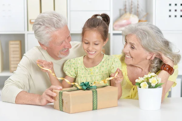 Grandparents and granddaughter with big gift box
