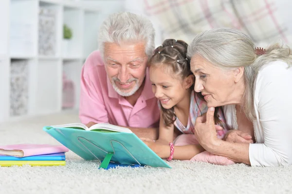 grandparents reading book with little  granddaughter