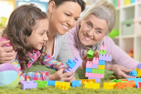 自宅のグリーン カーペットの上に横たわっている間カラフルなプラスチック製のブロックで遊んで幸せな笑顔の家族 — ストック写真